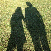 shadow of mother and daughter holding hands in a grass field