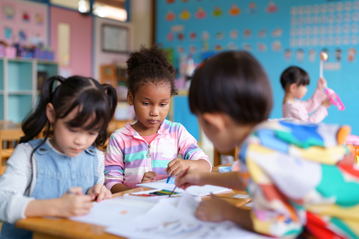 A group of elementary children practice drawing in classroom