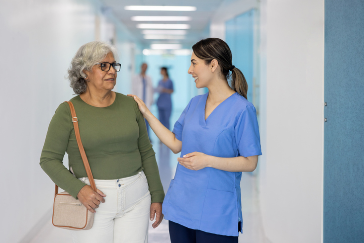 Friendly nurse greeting a senior woman at the hospital and smiling