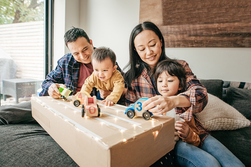 Two children play with wooden cars with caregivers
