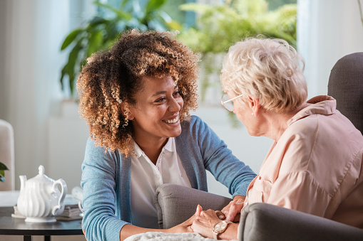 An older woman and her caregiver smile at each other